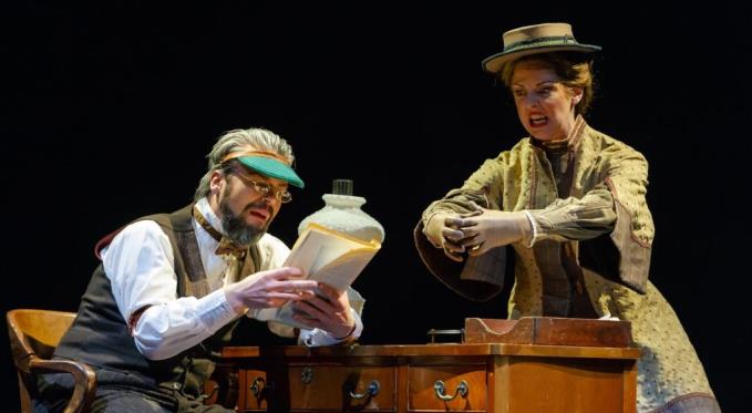 Mr. Dashwood (Daniel Teadt), publisher at The Daily Volcano , reads Jo’s (Corrie Stallings) manuscript while she enthusiastically demonstrates a key scene